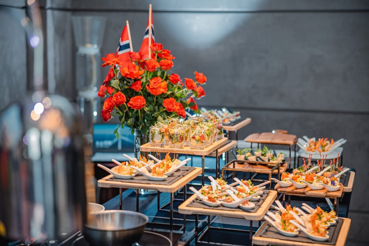 A luxurious buffet setup with gourmet dishes, roses, and flag decorations indoors.